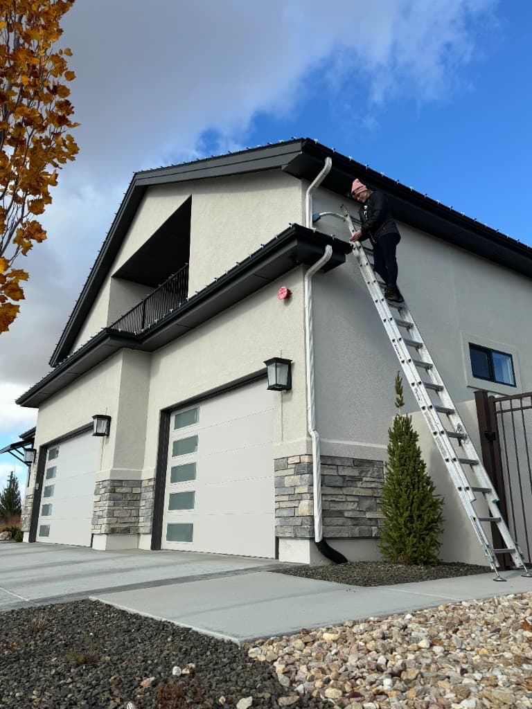 Boise neighborhood roofline with Christmas lights installed across multiple ridges
